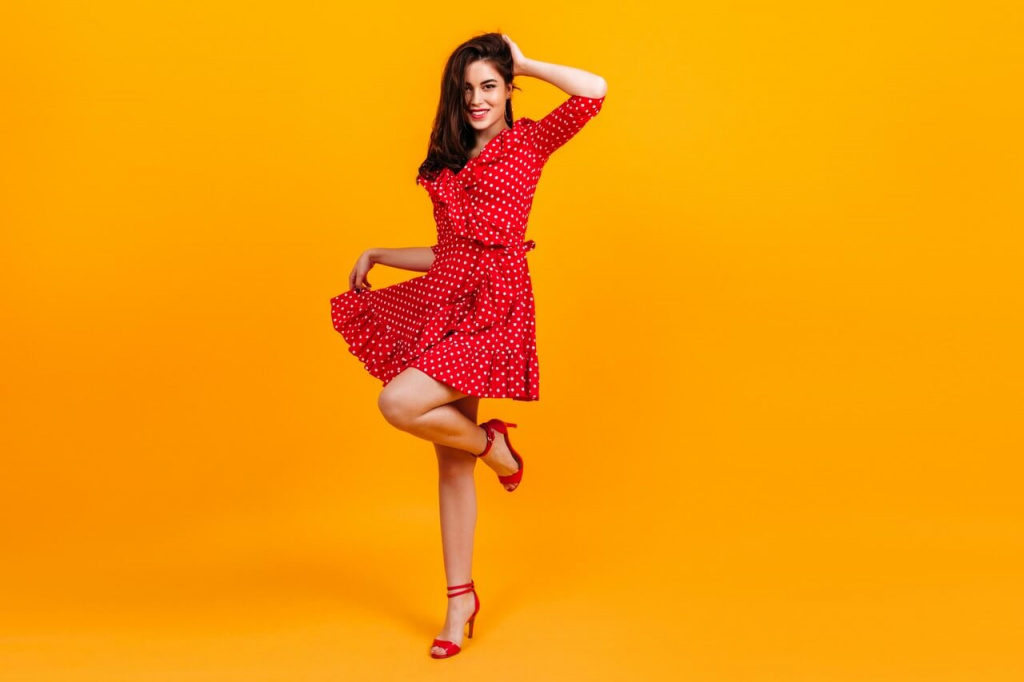 Девушка в красном платье стоит на 1 ноге